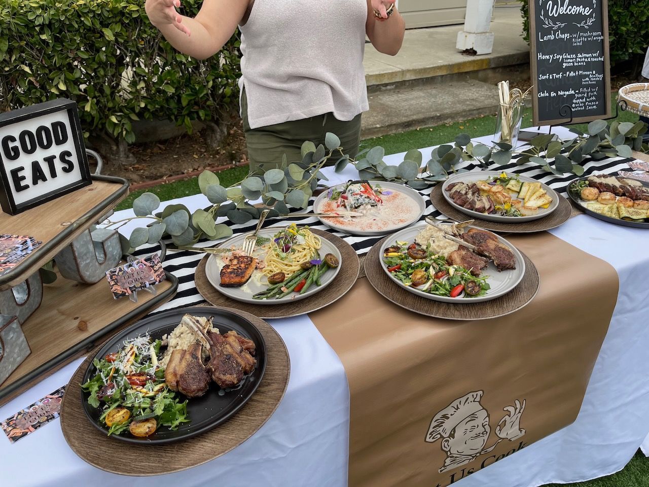A woman is standing in front of a table with plates of food on it.