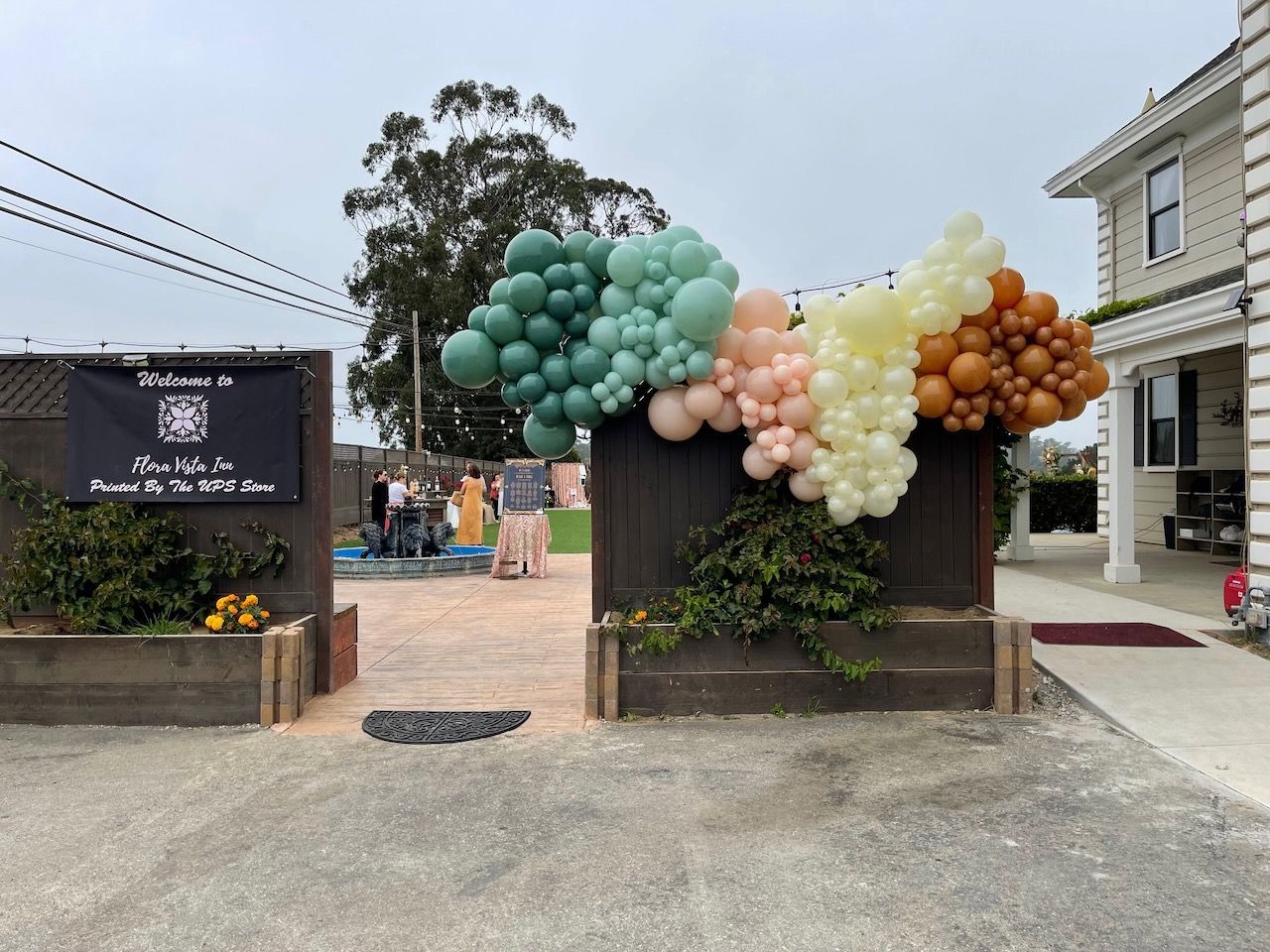 A bunch of balloons are hanging from a fence in front of a building.