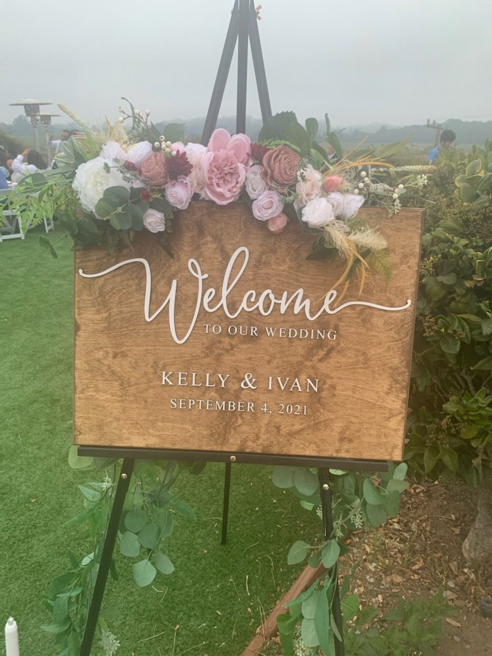 A wooden welcome sign is sitting on top of a wooden easel.