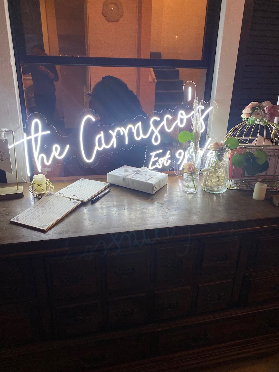 A neon sign that says `` the carrascos '' is on a window sill.