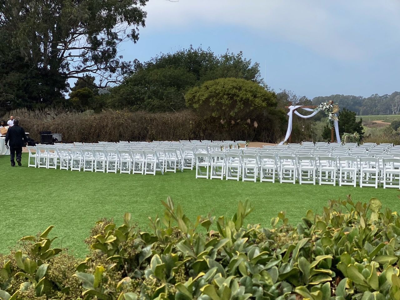 A row of white chairs are lined up in a grassy field.