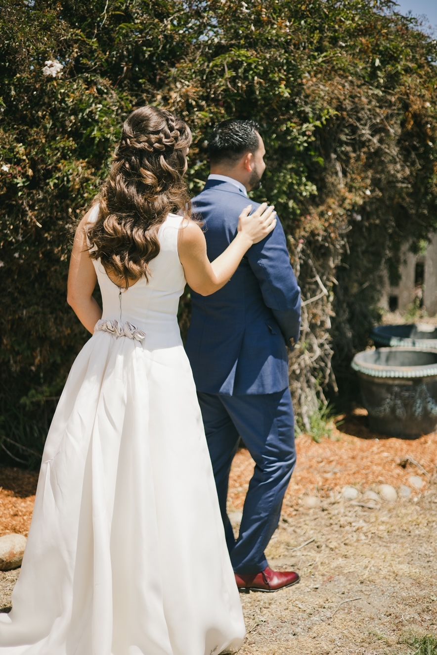 A bride and groom are standing next to each other in front of a fountain.