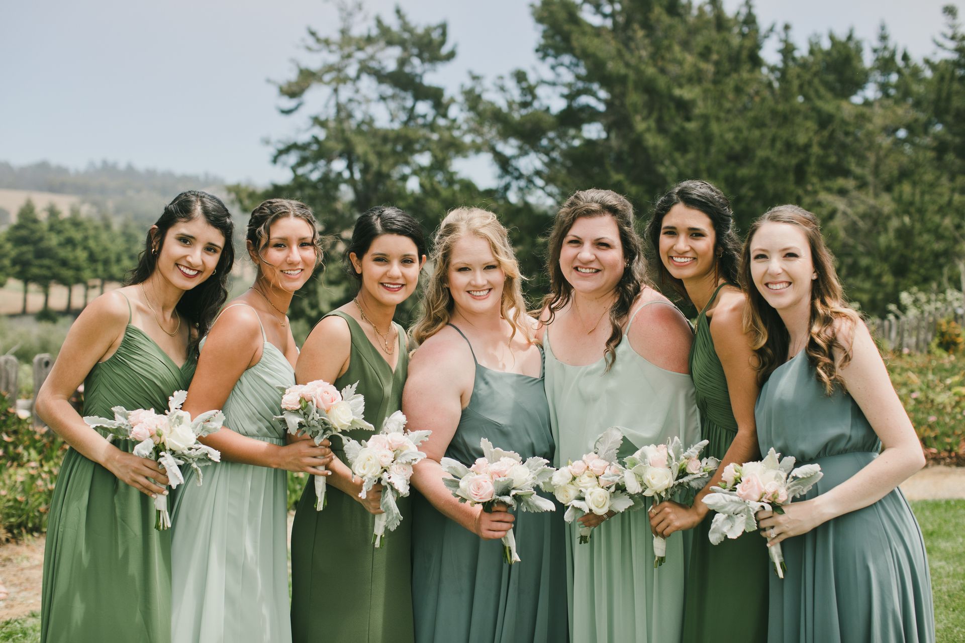 A group of bridesmaids in green dresses are posing for a picture.