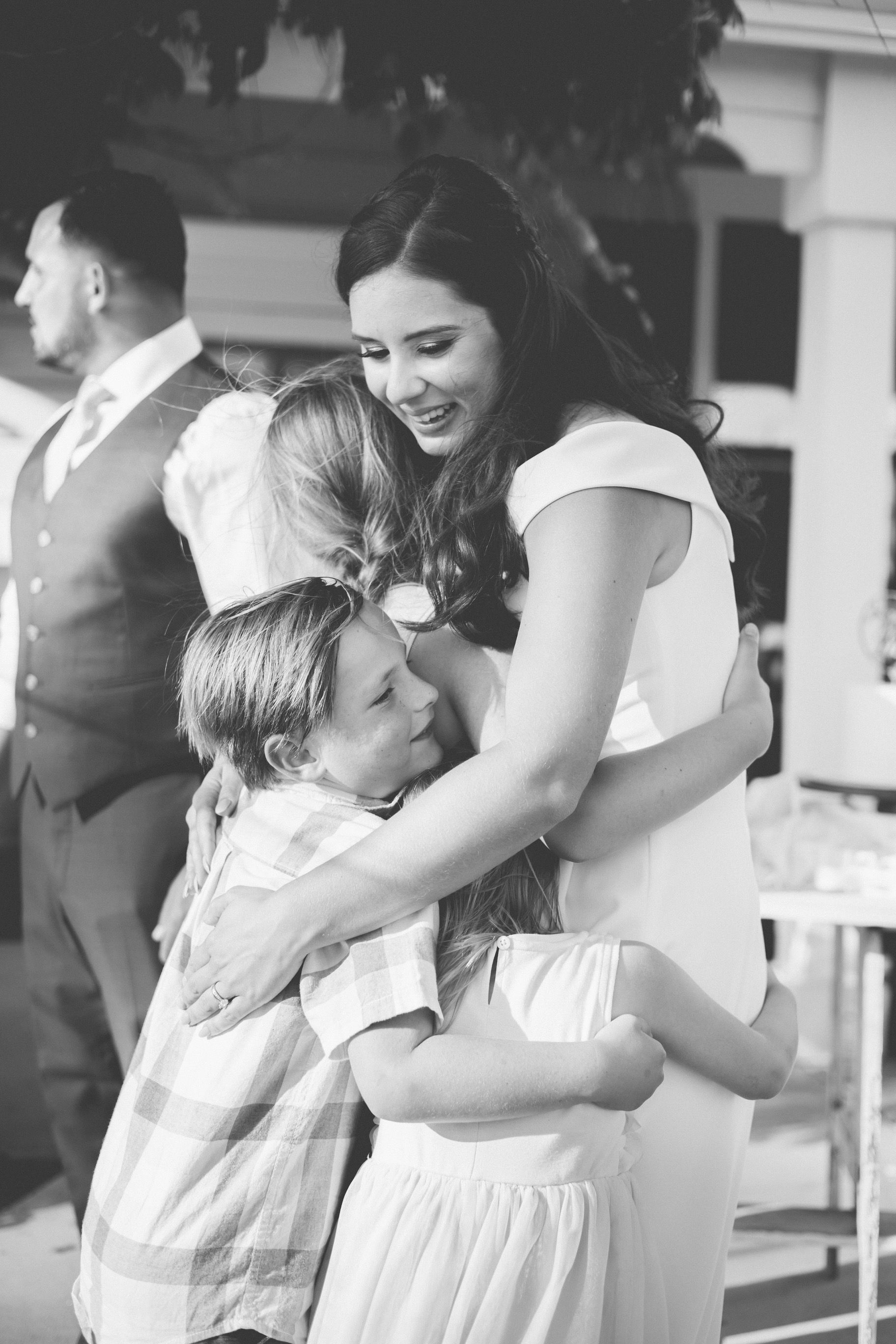 A woman is hugging two children at a wedding reception.