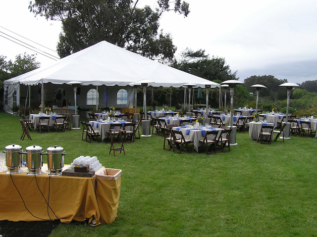 Tables and chairs under a tent in a grassy field