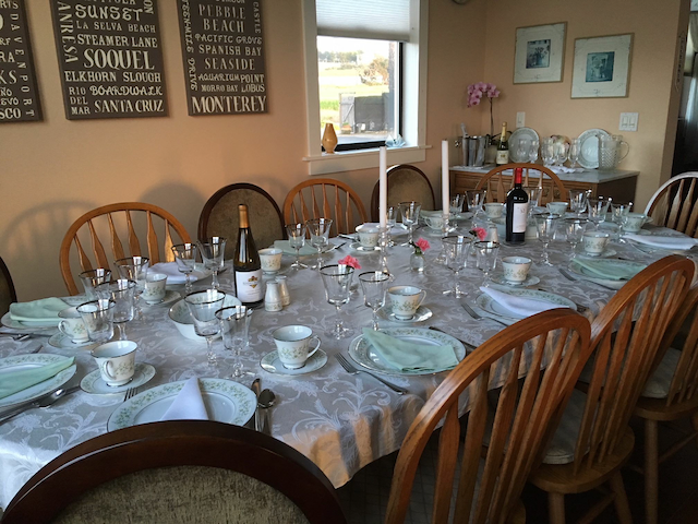 A long table with plates glasses and a bottle of wine