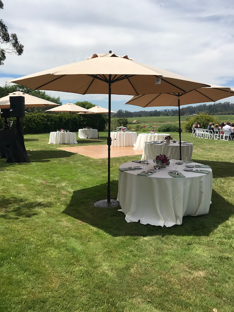 A lawn with tables and umbrellas in it