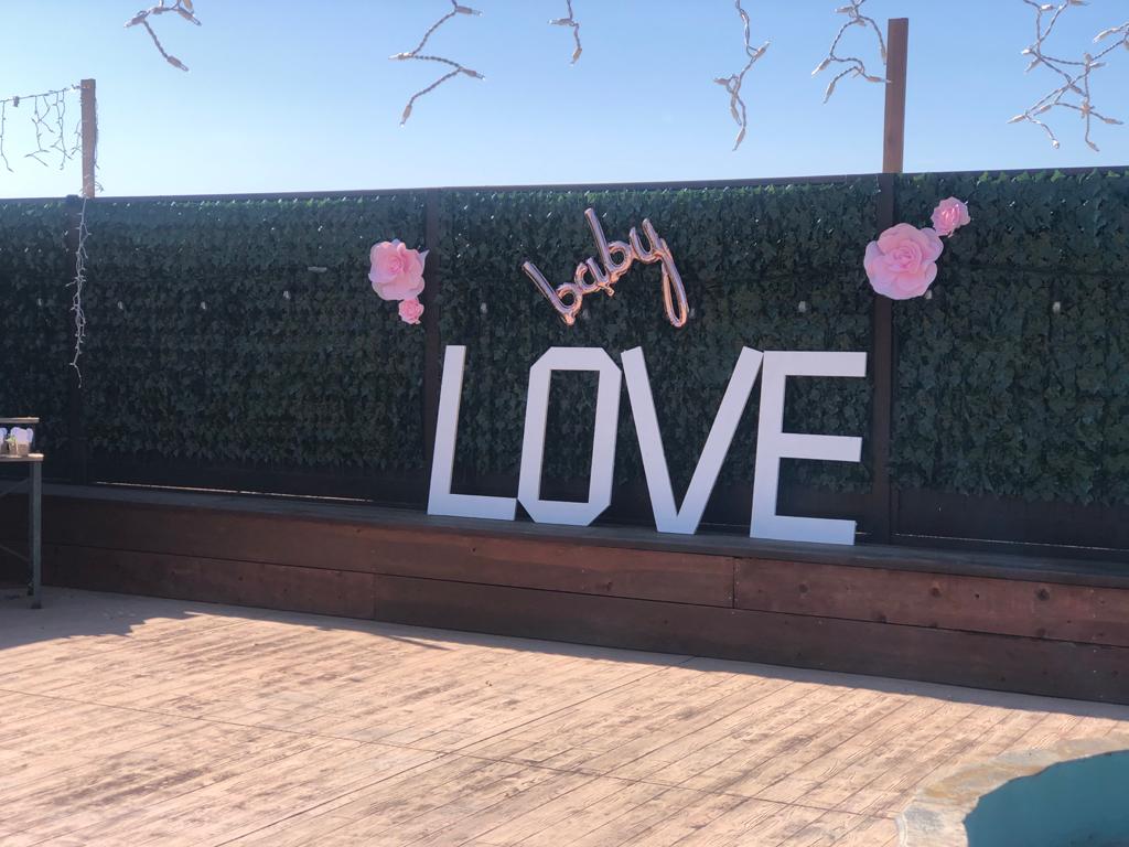 A sign that says baby love is hanging on a fence.