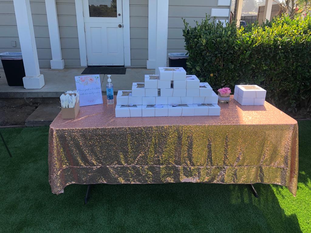 A table with a gold tablecloth is sitting on the grass in front of a house.