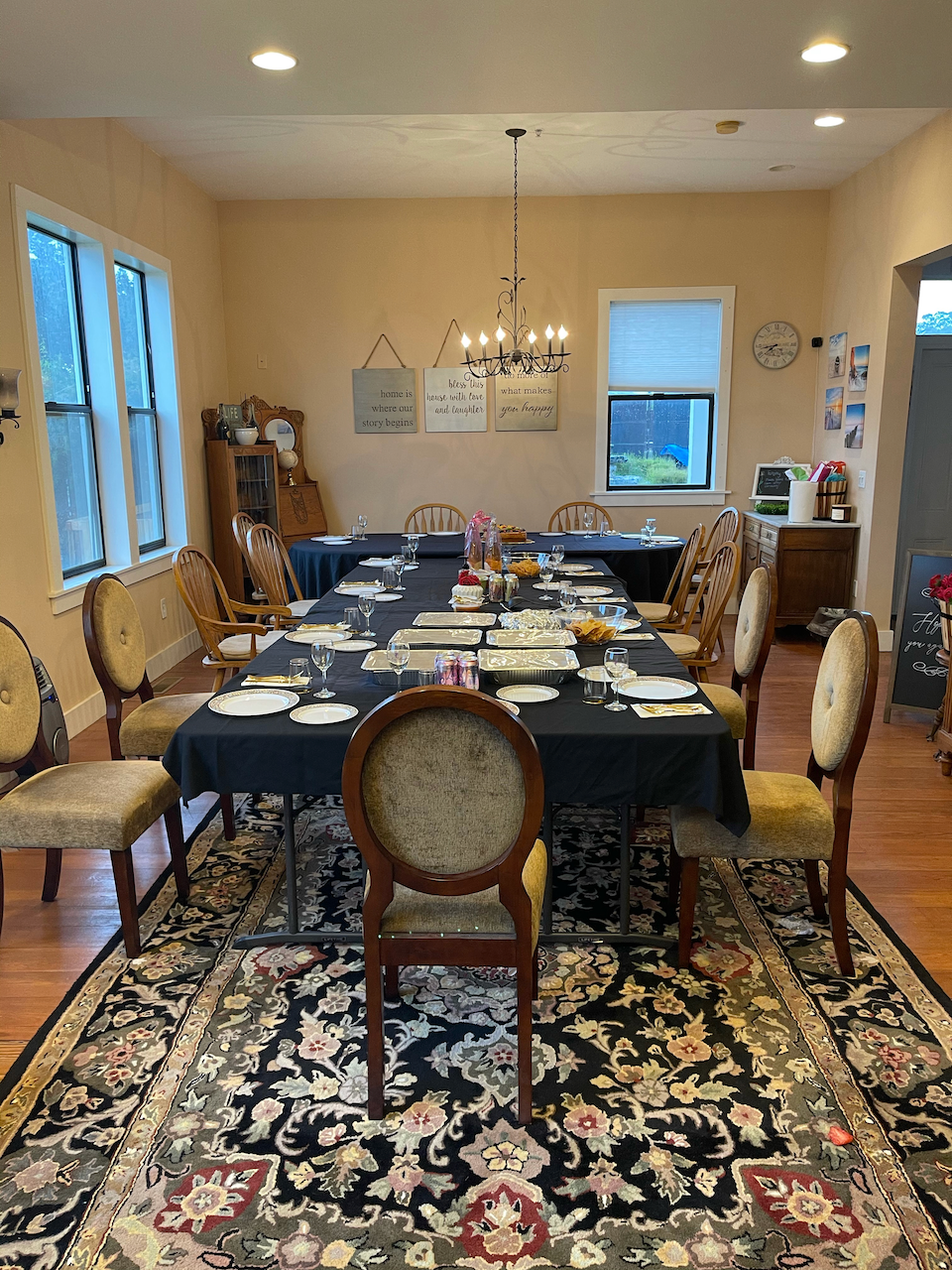A dining room with a long table and chairs and a rug.