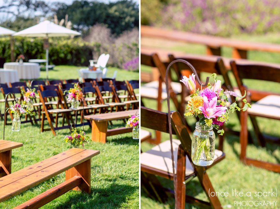 A wedding ceremony is taking place in a field with wooden chairs and benches.