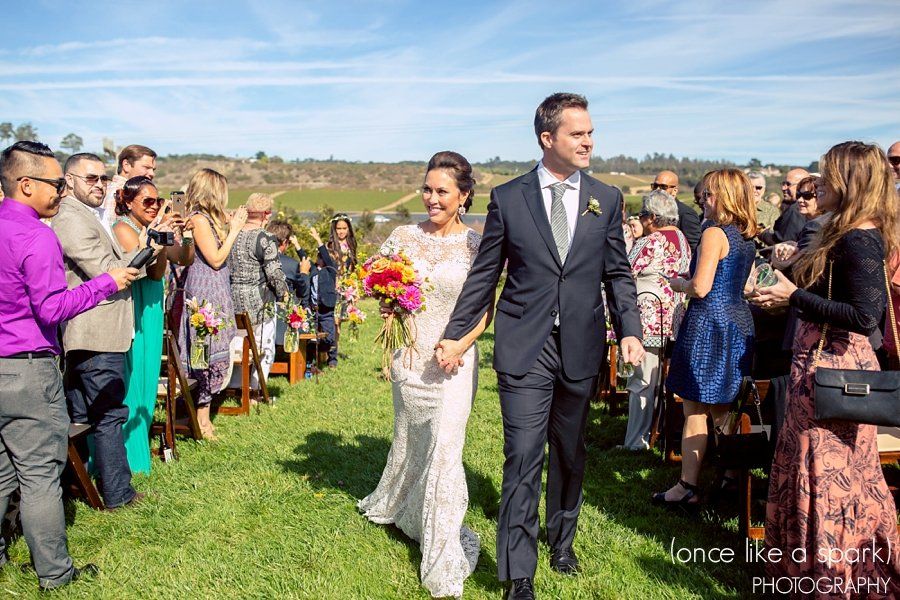A bride and groom are walking down the aisle at their wedding holding hands.