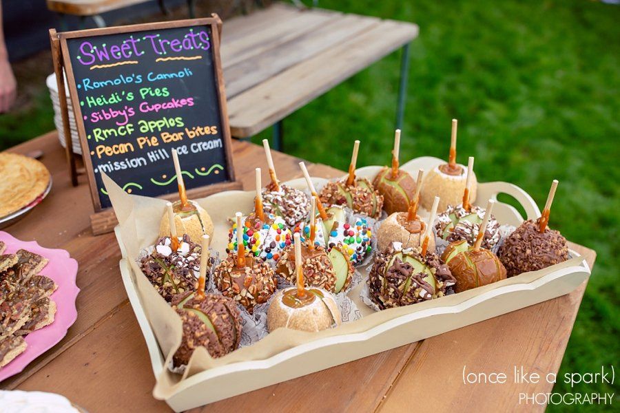 A tray of caramel apples with a sign that says sweet treats