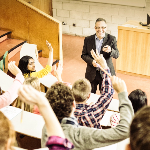 A group of people raising their hands in a lecture hall