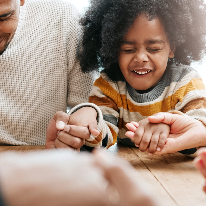 A man and a little girl are sitting at a table holding hands.