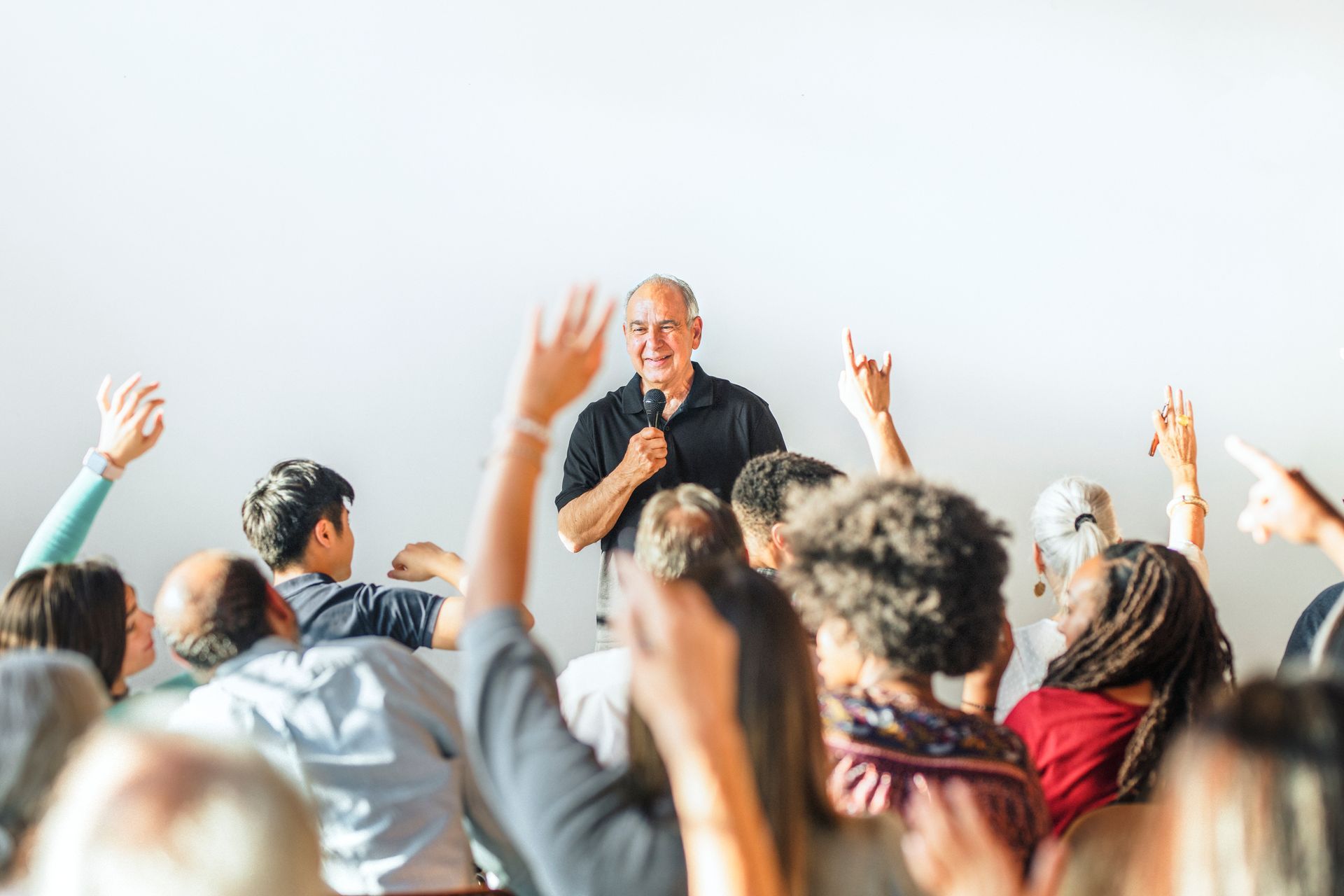 A man is giving a speech to a crowd of people with their hands up.