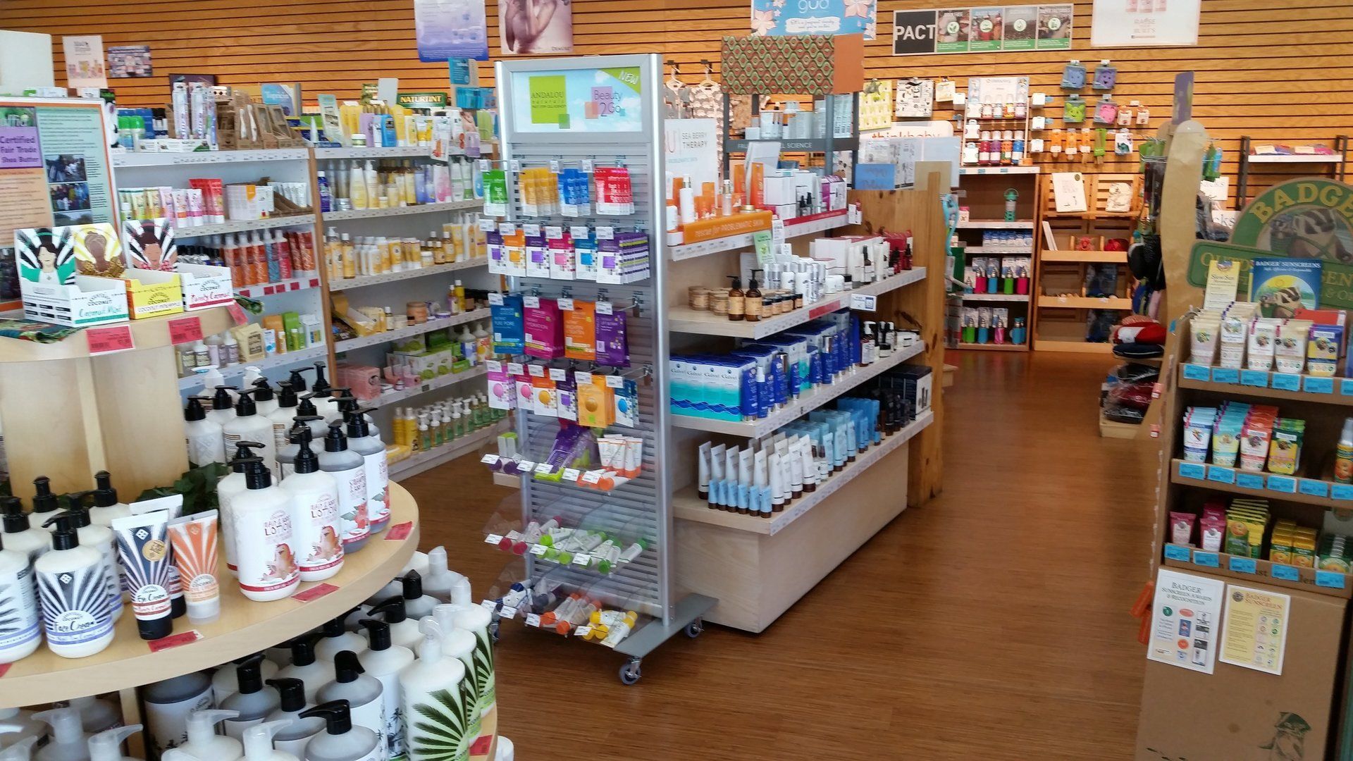 Shelves stocked with health and beauty products inside a well-lit store, wooden floors.