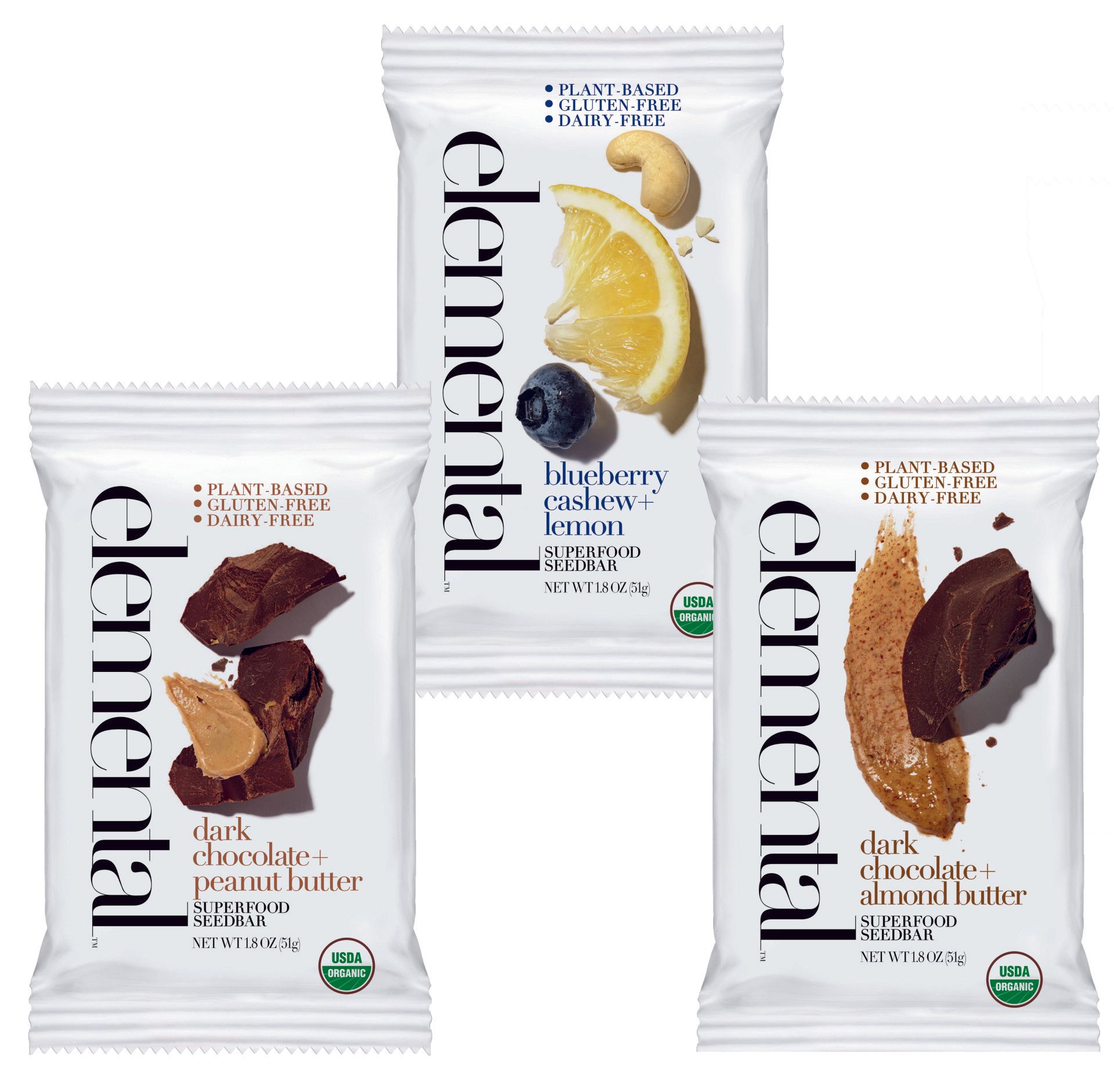 Three white Elemental snack bar wrappers. One features a blueberry, lemon, and cashew. Another shows chocolate and peanut butter. The third depicts chocolate and almond butter.