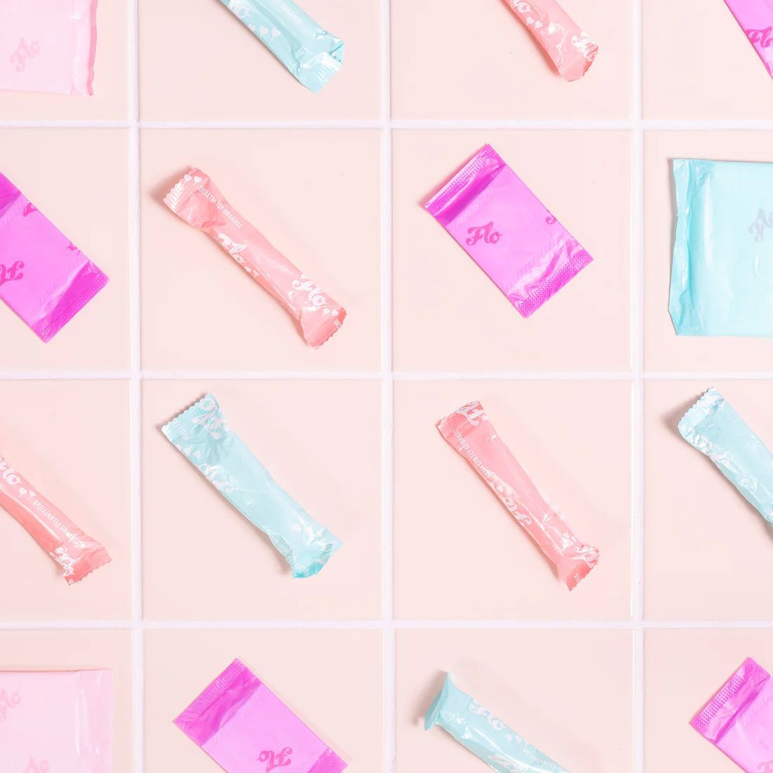 Pink and teal packaged feminine hygiene products arranged on a pink tiled surface.