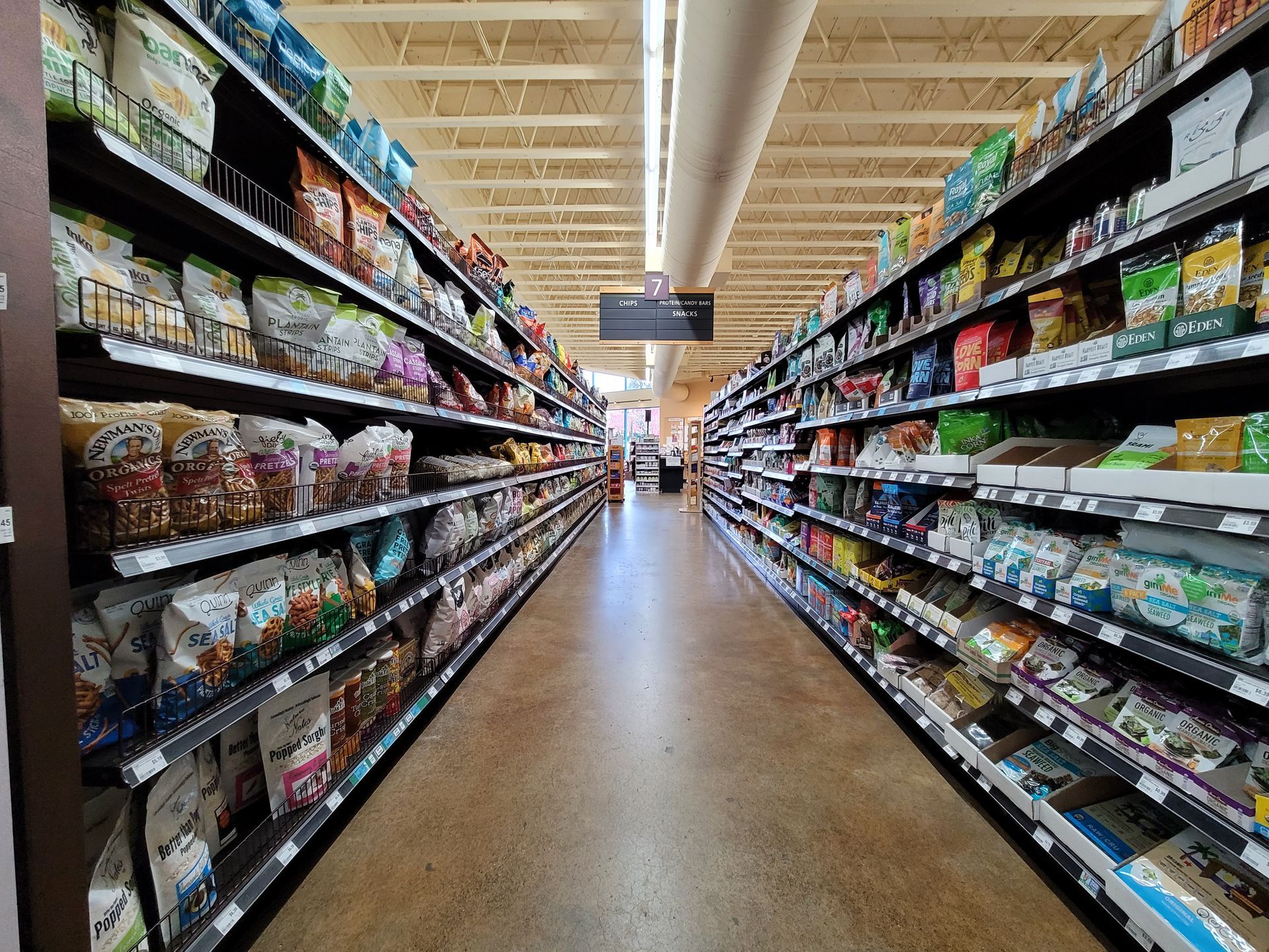 Grocery store aisles lined with snack products; neutral lighting.
