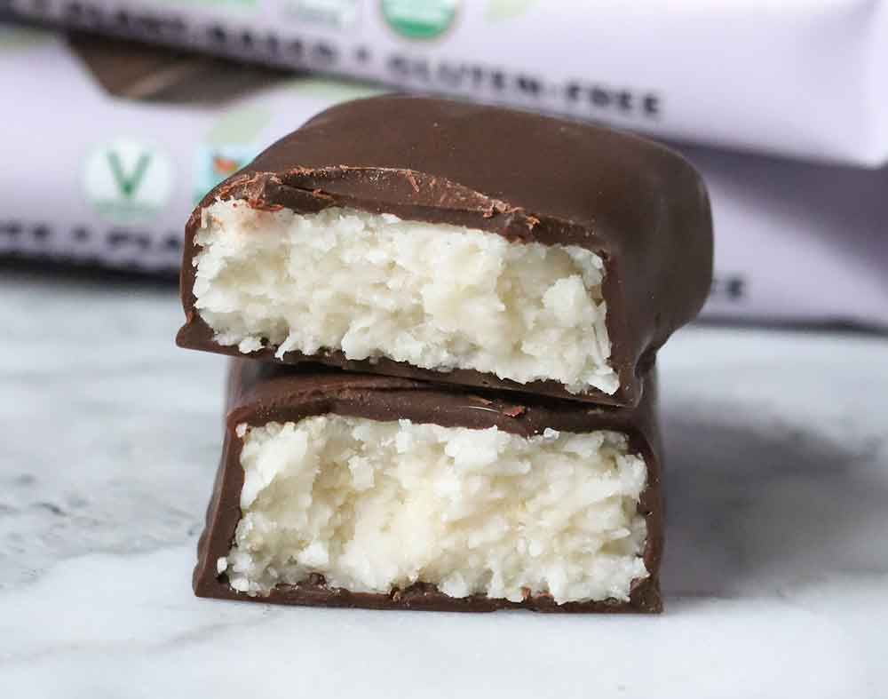 Two halves of a chocolate-covered coconut bar stacked, showing a white, shredded coconut filling.