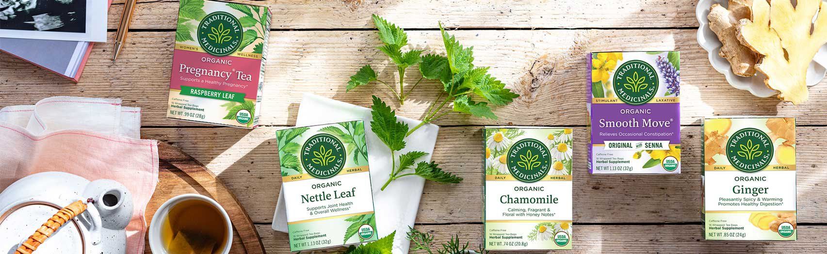 Assortment of tea boxes on a wooden surface with various flavors like chamomile, lemon ginger, and more.