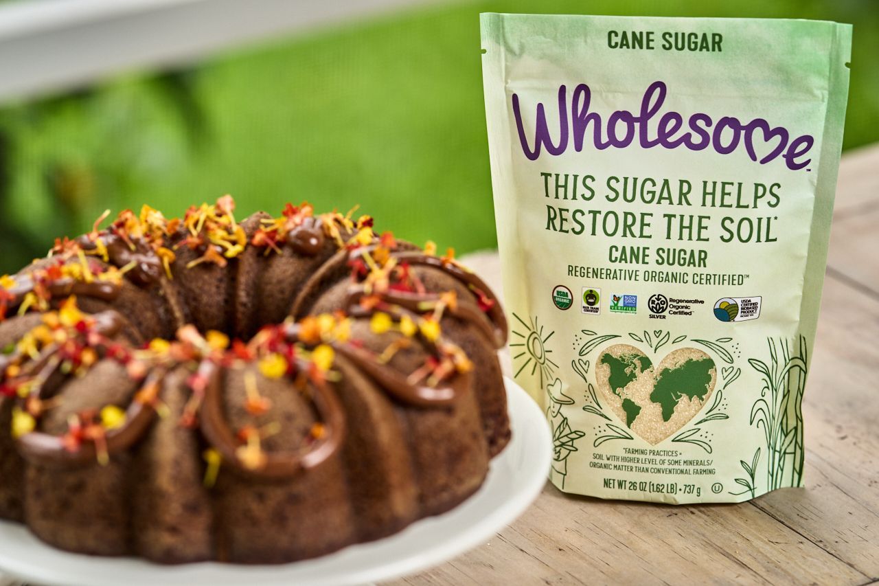 A chocolate cake with frosting and colorful toppings next to a bag of 