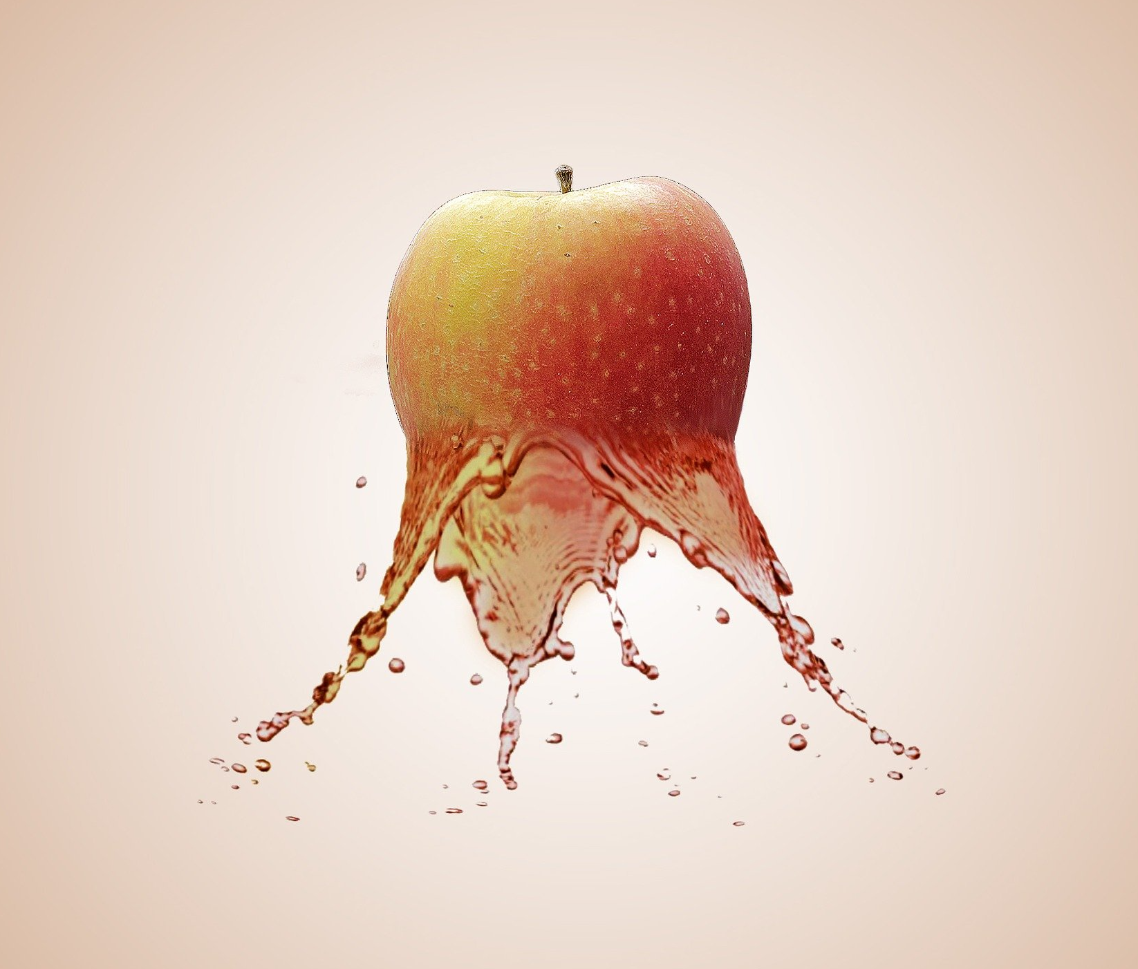Apple with red and yellow skin, water is splashing out below.