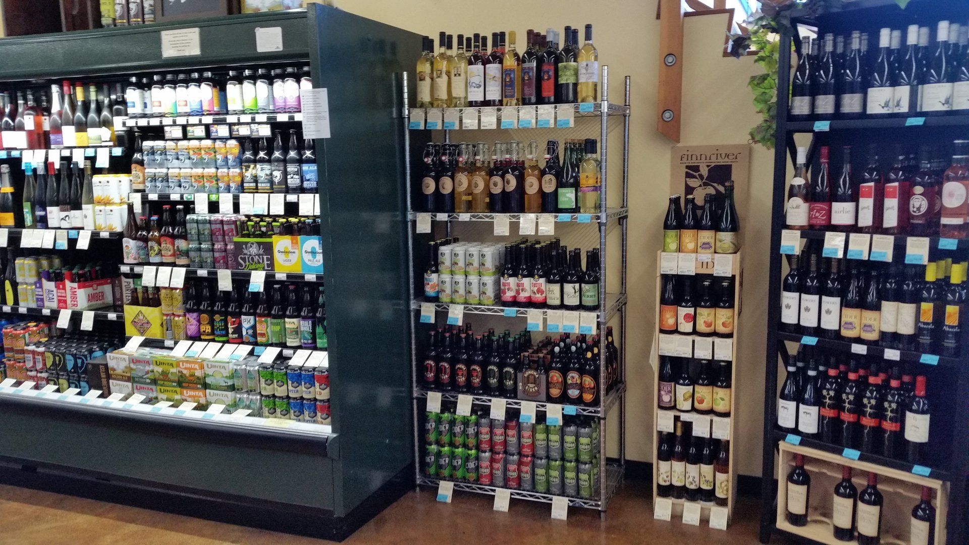 Shelves stocked with various alcoholic beverages in a store. Refrigerated and open shelves of beer and wine.