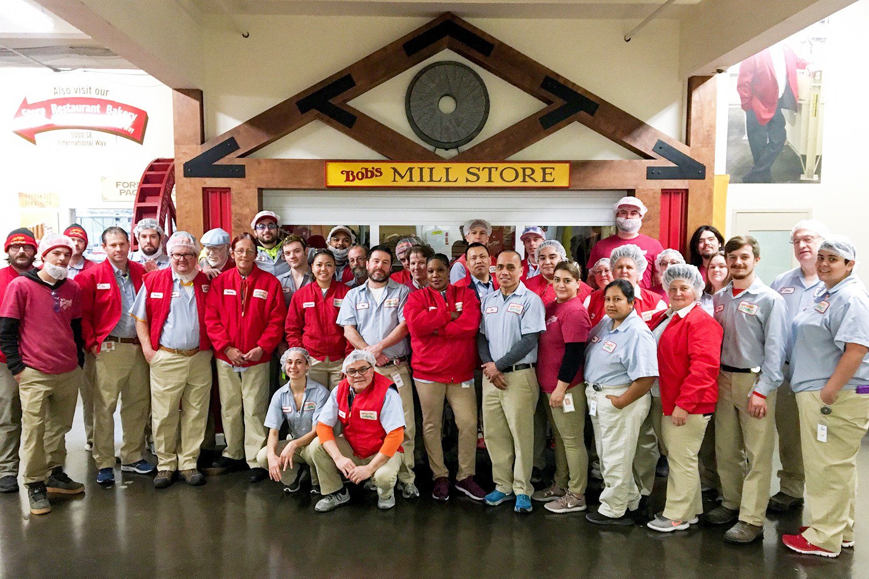 Group of employees in red and tan uniforms pose in front of a 
