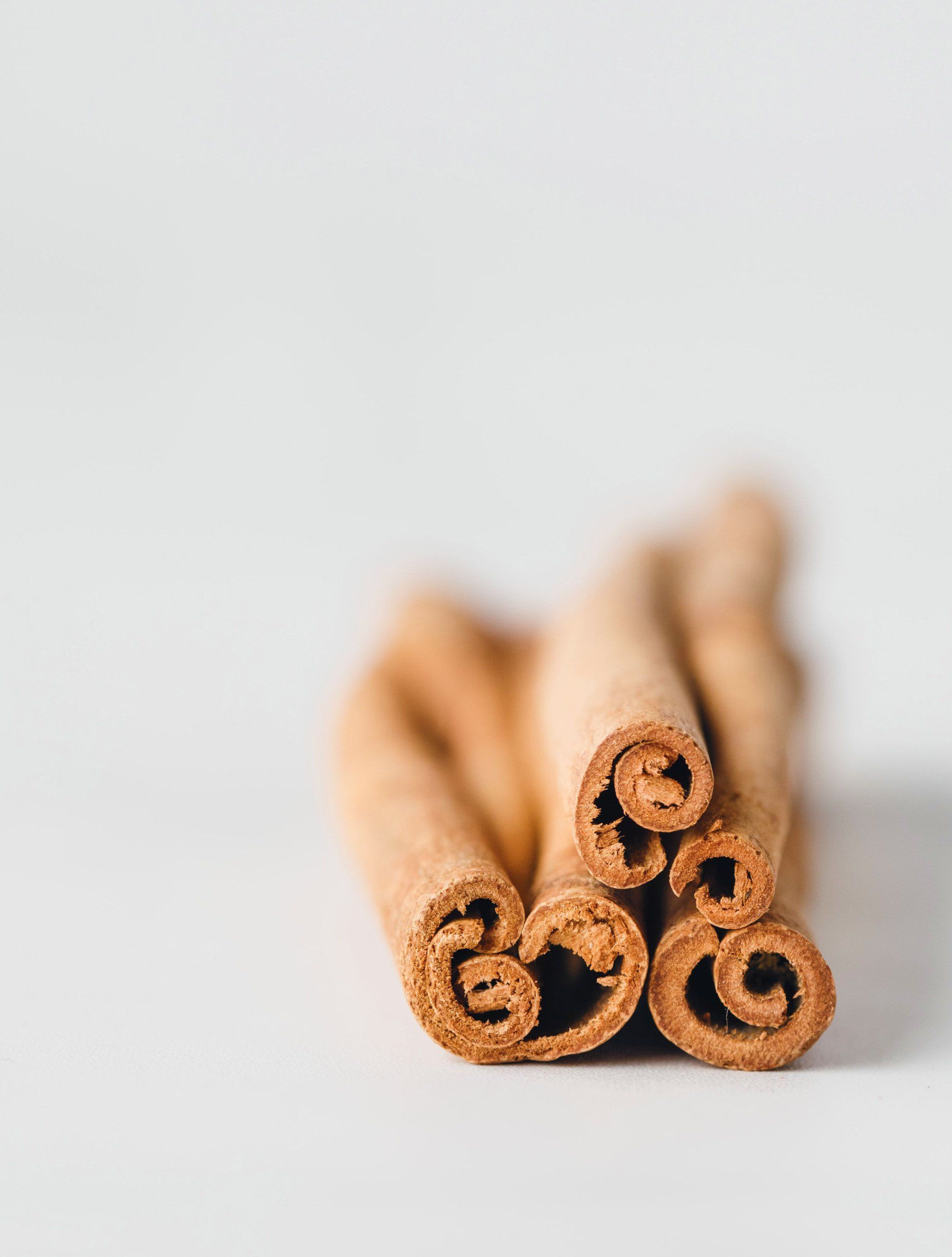 Cinnamon sticks, a bundle of brown, rolled bark, rest against a white background.