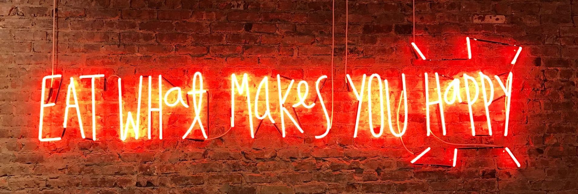 Neon sign on a brick wall that reads 