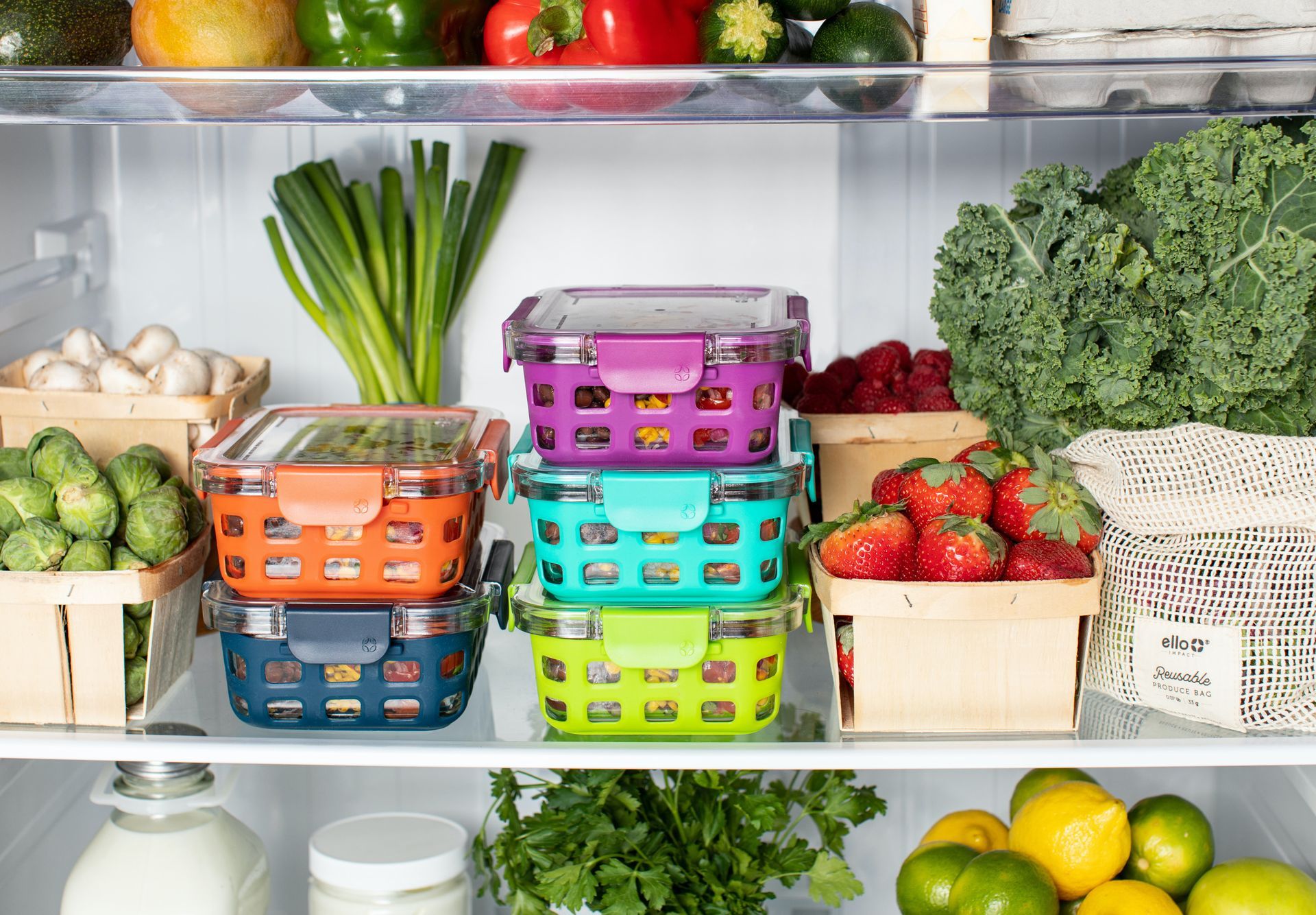 A refrigerator shelf filled with colorful containers of produce, including berries, leafy greens, and vegetables.