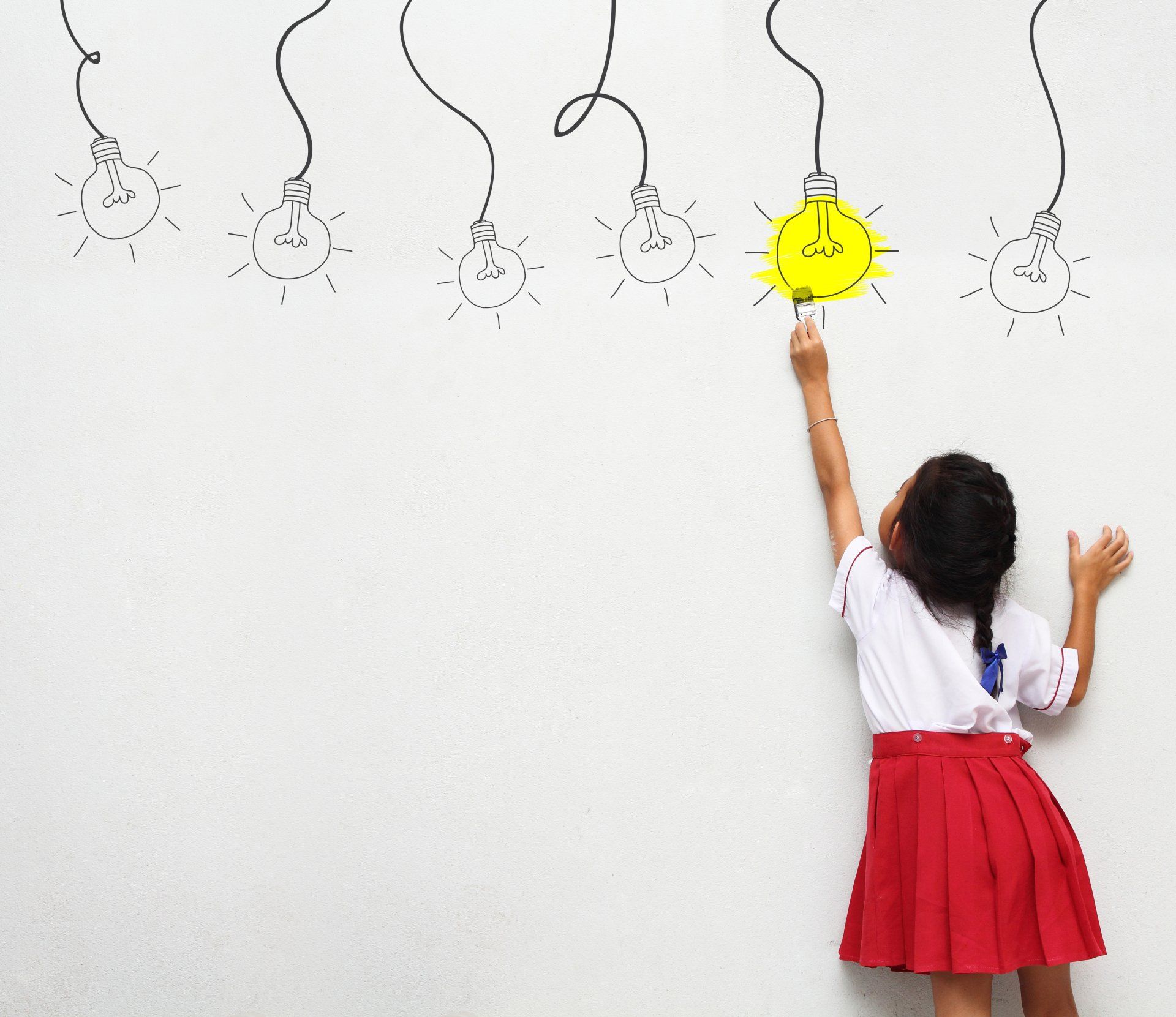 A young girl in a red skirt reaches up to touch a glowing yellow lightbulb drawn on a white wall with other unlit bulbs.