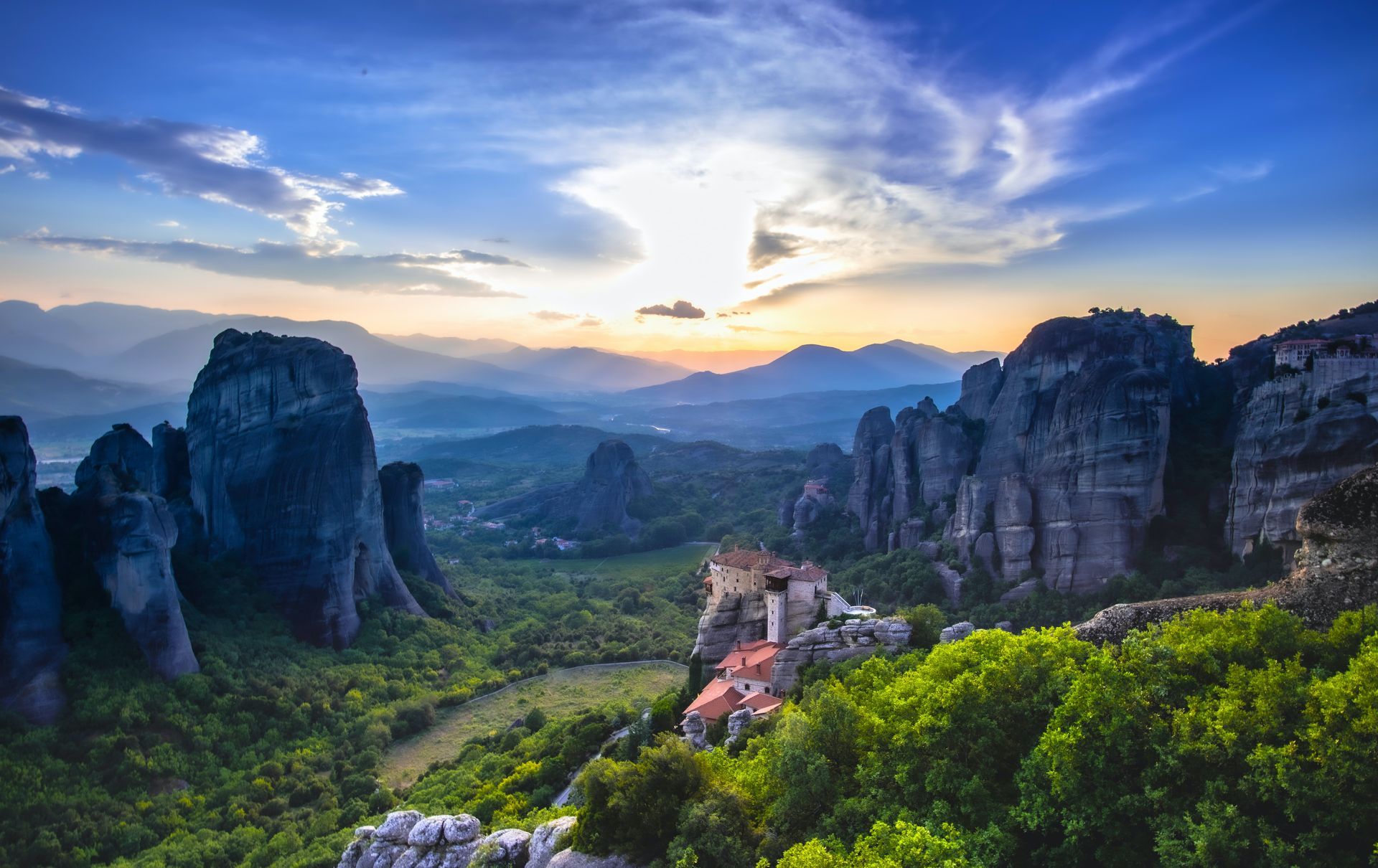 Sunset over Meteora monasteries perched on towering rock formations, Greece.