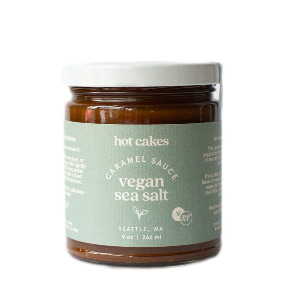 A jar of Hot Cakes Vegan Sea Salt Caramel Sauce, in a glass jar with a white lid and a light green label.