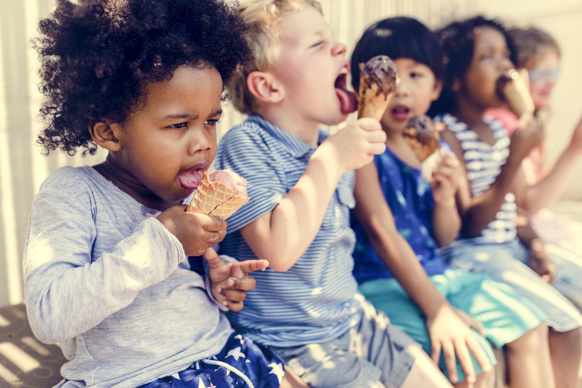A diverse group of children enjoying ice cream cones, showing expressions of delight.