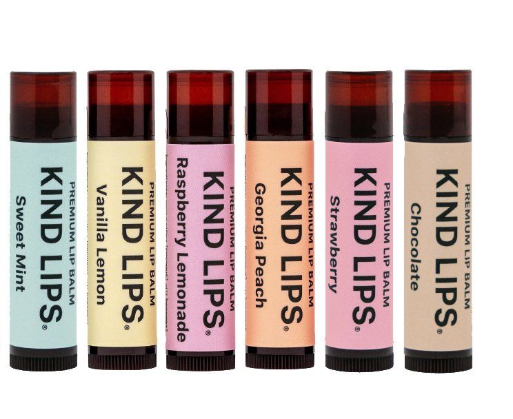 Six Kind Lips lip balms in various flavors. The tubes have different colored labels and dark caps, arranged in a row.
