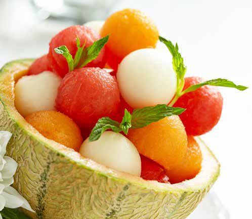 Melon bowl filled with fruit balls, including watermelon, cantaloupe, and honeydew, garnished with mint.