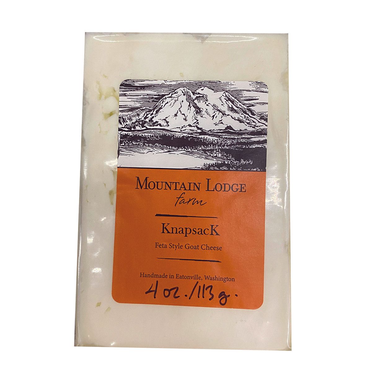 A packaged block of Mountain Lodge Farm Knapsack goat cheese. The label is orange with black text and a mountain illustration.