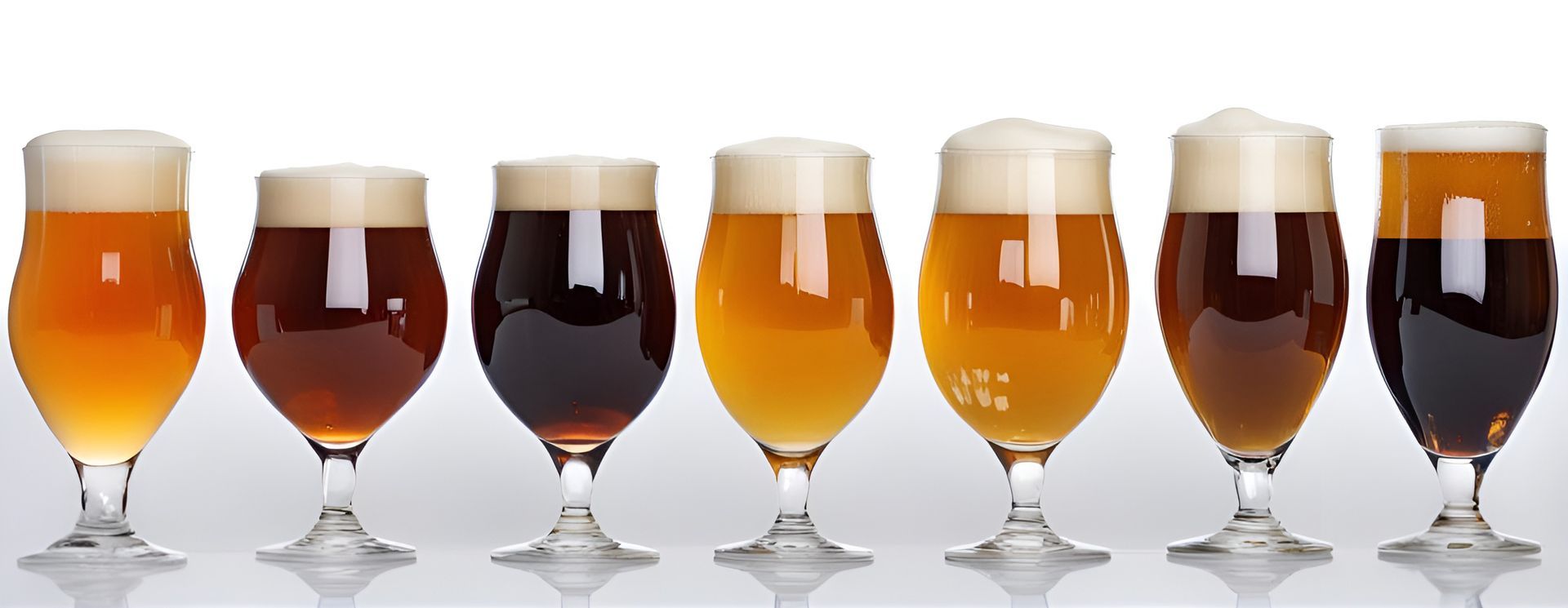 Glasses of beer in various colors arranged in a row, showing the range from light amber to dark brown.