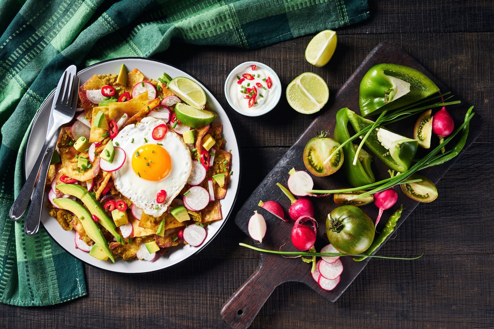 Chilaquiles with egg, avocado, and radish. Ingredients on a wooden board.