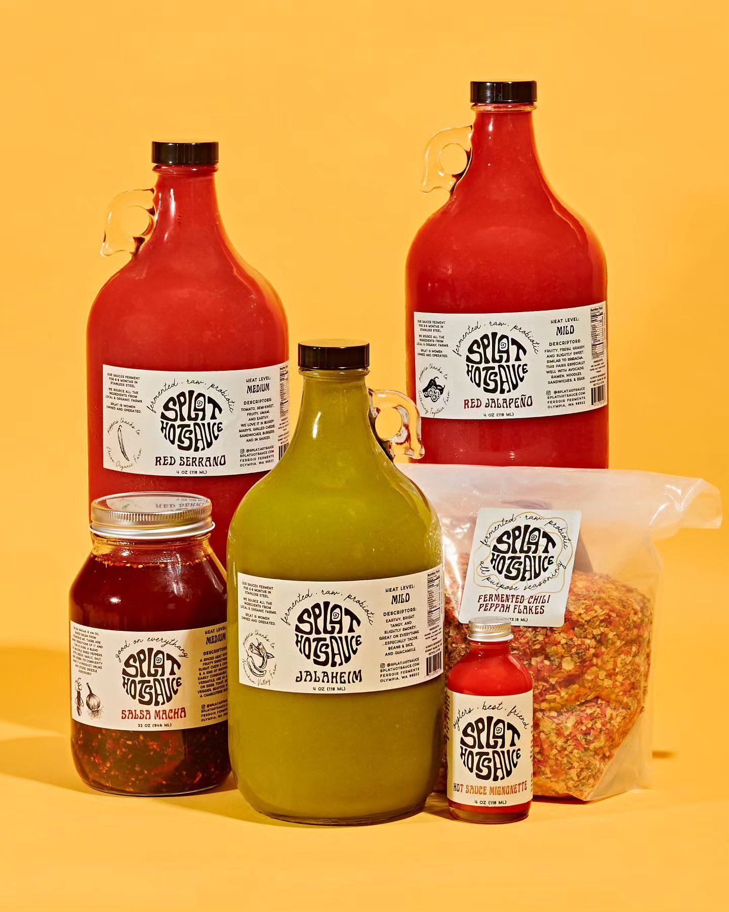 Assortment of red and green hot sauces and spices in various sized glass bottles and jars on a yellow background.