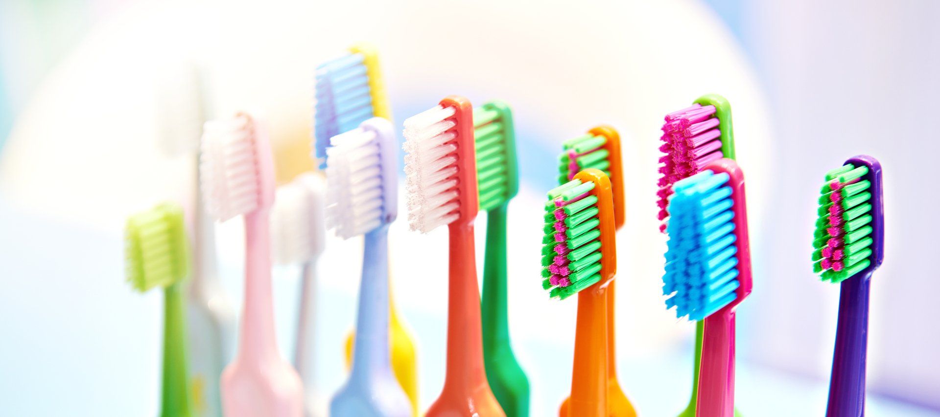 A collection of colorful toothbrushes with various brush and handle colors, arranged closely together.