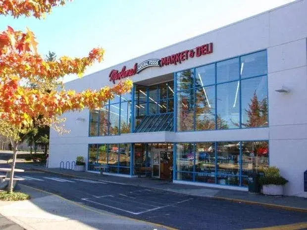 Exterior view of Redland Market & Deli store with glass windows, a sunny day, and autumn trees.