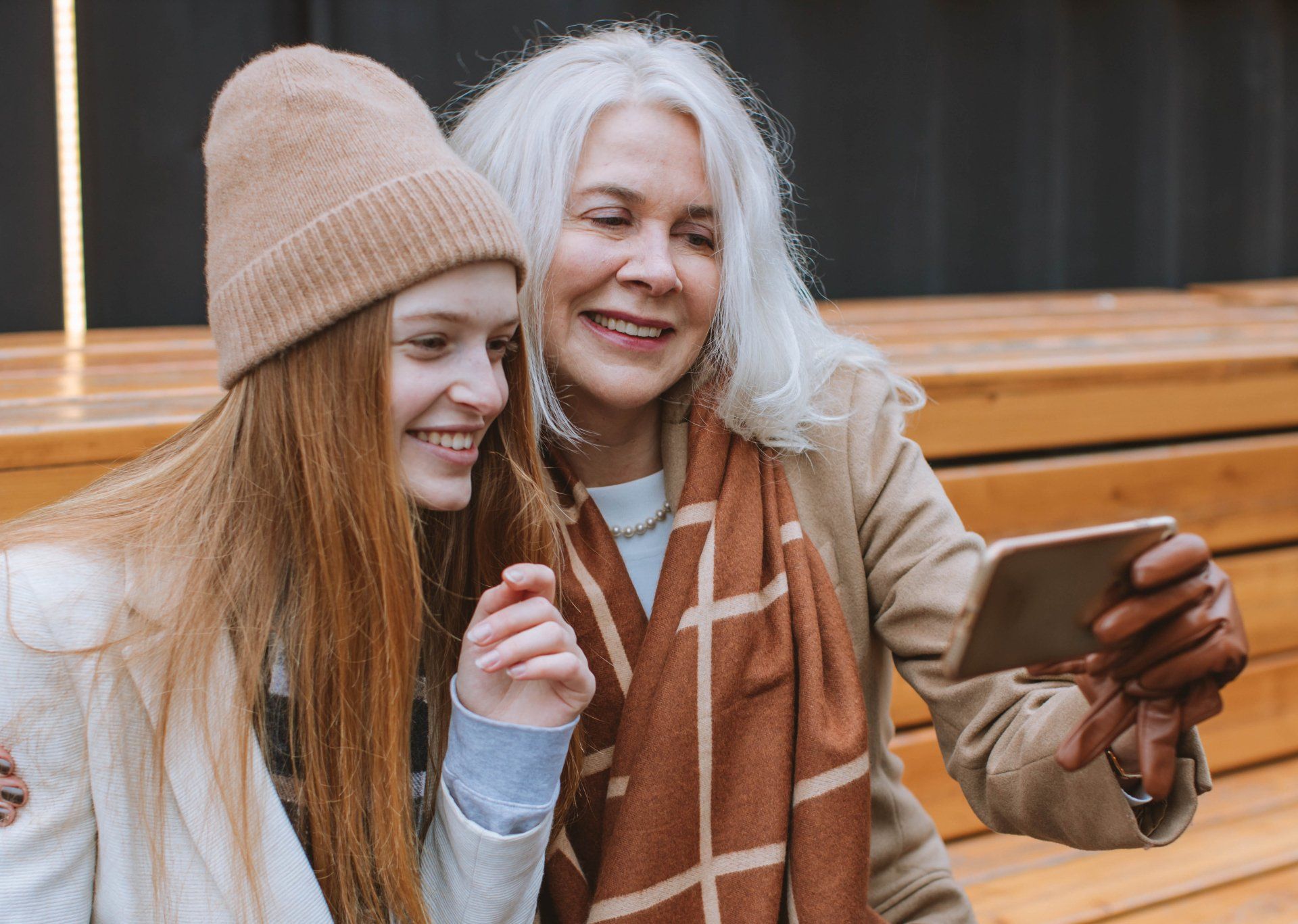Woman and young person with long hair taking a selfie outdoors, both smiling.