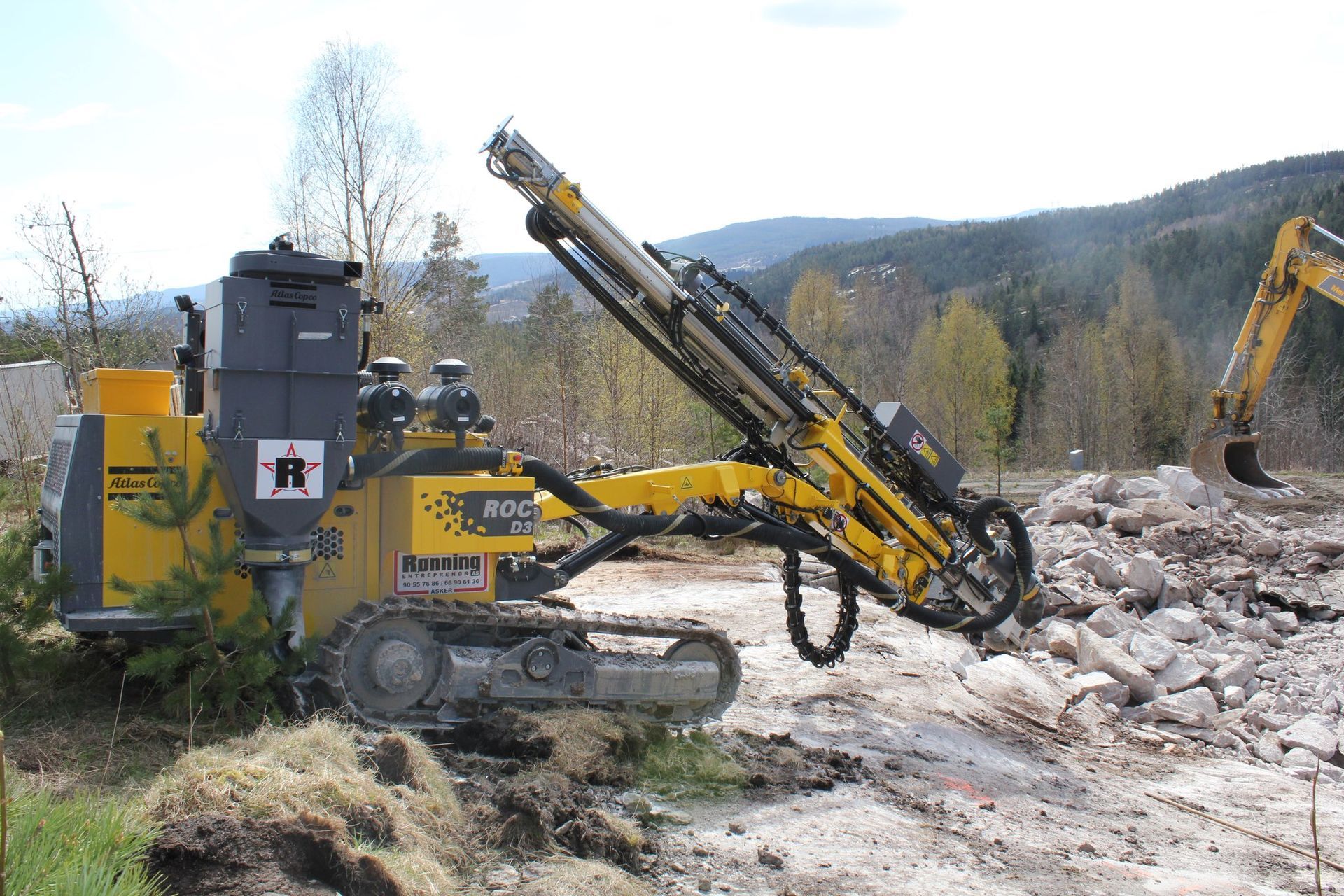 Gul borerigg på spor som borer i steiner, utendørs.