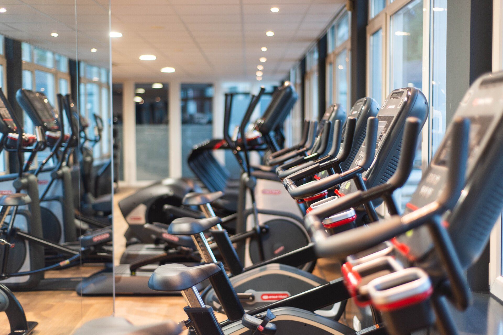 Sportschool met fitnessapparatuur op een rij, waaronder crosstrainers en hometrainers.