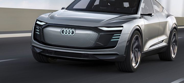 A silver audi concept car is driving down a road.