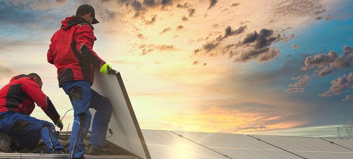 Two men are installing solar panels on a roof.